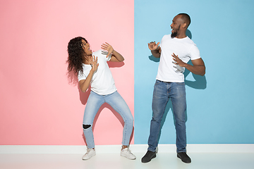 Image showing Young emotional man and woman on pink and blue background