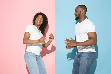 Image showing Young emotional man and woman on pink and blue background