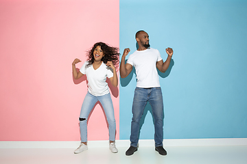 Image showing Young emotional man and woman on pink and blue background