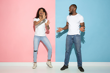 Image showing Young emotional man and woman on pink and blue background