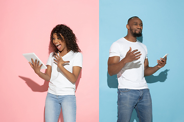 Image showing Young emotional man and woman on pink and blue background