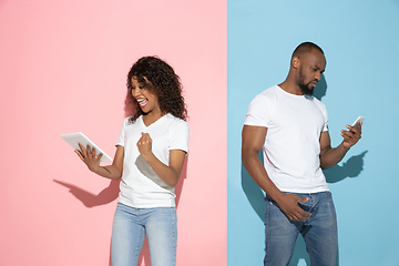 Image showing Young emotional man and woman on pink and blue background