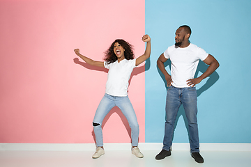 Image showing Young emotional man and woman on pink and blue background