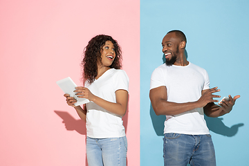 Image showing Young emotional man and woman on pink and blue background