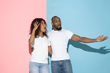 Image showing Young emotional man and woman on pink and blue background