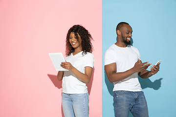 Image showing Young emotional man and woman on pink and blue background