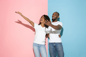 Image showing Young emotional man and woman on pink and blue background