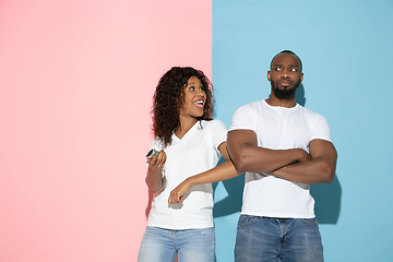 Image showing Young emotional man and woman on pink and blue background