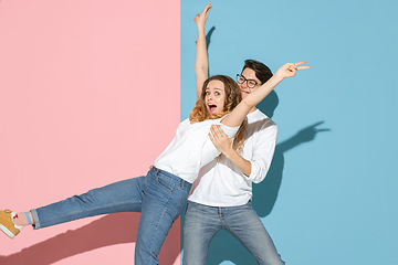 Image showing Young emotional man and woman on pink and blue background