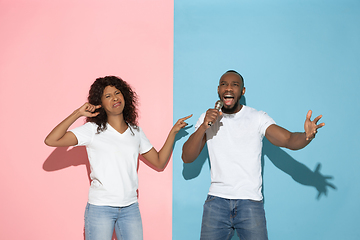 Image showing Young emotional man and woman on pink and blue background