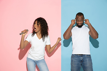 Image showing Young emotional man and woman on pink and blue background