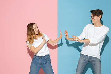 Image showing Young emotional man and woman on pink and blue background