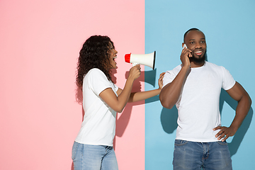 Image showing Young emotional man and woman on pink and blue background