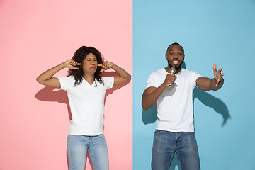 Image showing Young emotional man and woman on pink and blue background