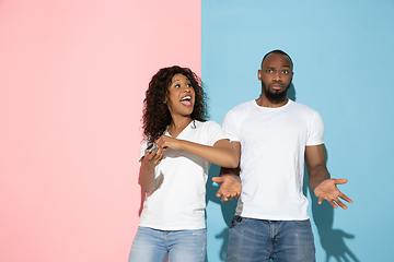 Image showing Young emotional man and woman on pink and blue background