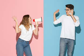 Image showing Young emotional man and woman on pink and blue background