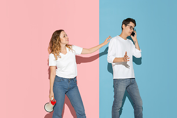 Image showing Young emotional man and woman on pink and blue background