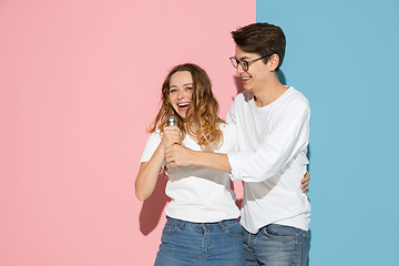 Image showing Young emotional man and woman on pink and blue background