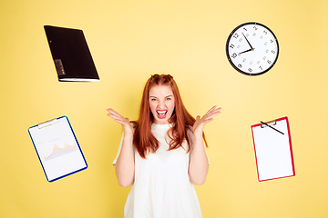 Image showing Caucasian young woman\'s portrait on yellow background, too much tasks