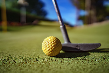 Image showing Mini Golf yellow ball with a bat near the hole at sunset