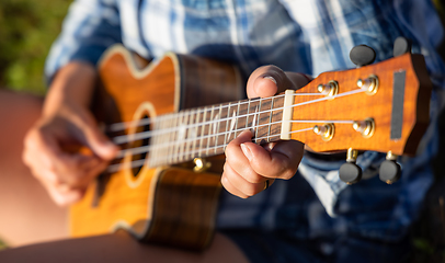 Image showing Woman at sunset playing the ukulele