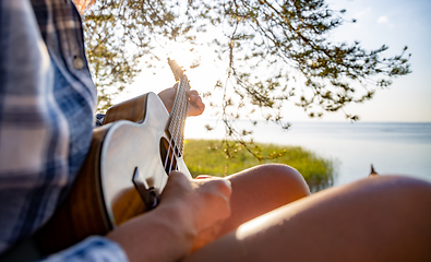 Image showing Woman at sunset playing the ukulele