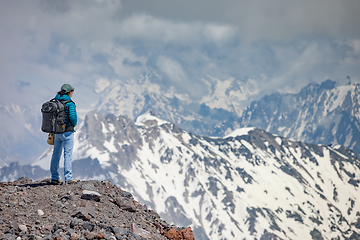 Image showing Hiker woman standing up achieving the top. View at the snowy mou