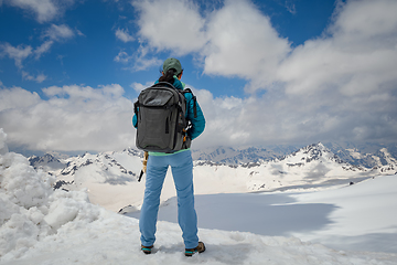 Image showing Hiker woman standing up achieving the top. View at the snowy mou