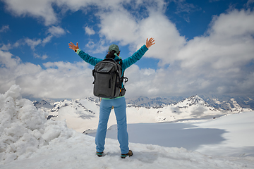 Image showing Hiker woman standing up achieving the top. View at the snowy mou