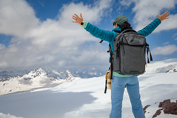 Image showing Hiker woman standing up achieving the top. View at the snowy mou