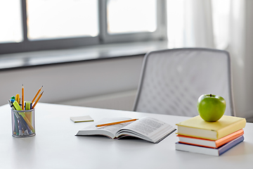 Image showing books, apple and school supplies on table at home