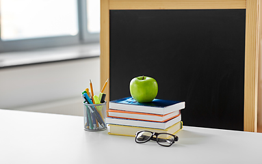 Image showing books, apple and school supplies on table at home