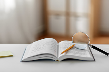 Image showing book with magnifier and pencil on table at home