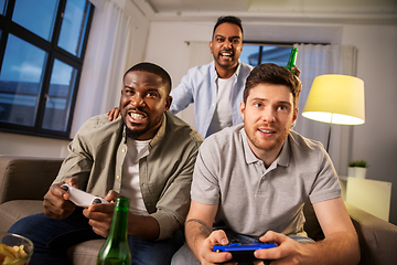 Image showing happy friends playing video games at home at night