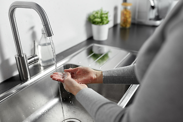 Image showing woman washing hands with liquid soap in kitchen