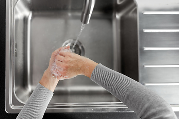 Image showing woman washing hands with soap in kitchen