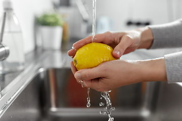 Image showing close up of woman washing lemon fruit in kitchen