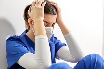 Image showing sad doctor or nurse in face mask holding to head