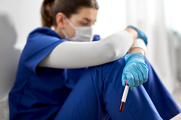 Image showing sad doctor or nurse holding beaker with blood test