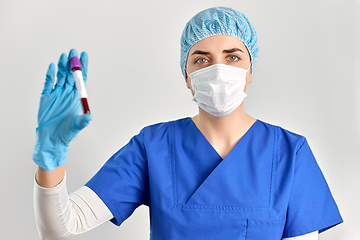 Image showing doctor in face mask holding beaker with blood test