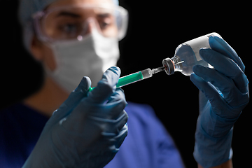 Image showing doctor in face mask with syringe and medicine