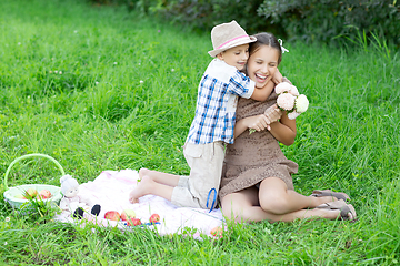 Image showing Little boy and teen age girl having picnic outdoors