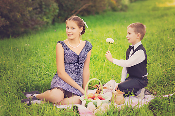 Image showing Little boy and teen age girl having picnic outdoors