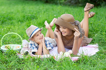 Image showing Little boy and teen age girl having picnic outdoors