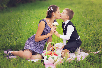 Image showing Little boy and teen age girl having picnic outdoors