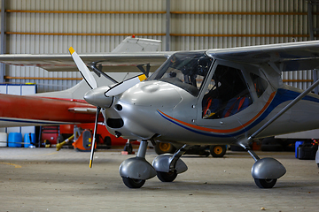 Image showing outdoor shot of small plane standing in shed