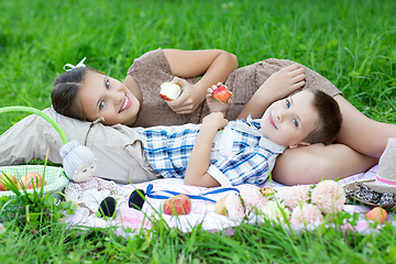 Image showing Little boy and teen age girl having picnic outdoors