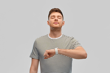 Image showing calm young man with smart watch meditating