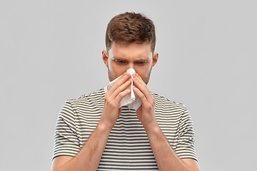 Image showing young man with paper tissue blowing his nose