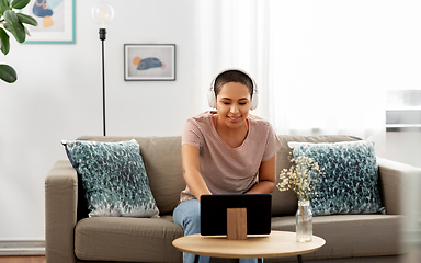 Image showing woman with headphones and tablet computer at home